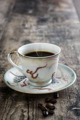 Coffee cup vintage style and beans coffee on a rustic wooden table

