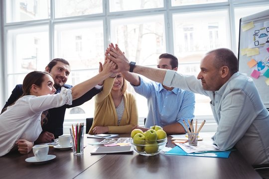 Coworkers giving high-five in meeting room