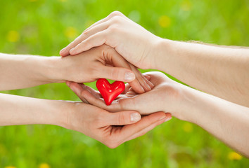 Man's hand proposing a red heart to woman's hand