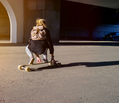  Young girl riding on a longboard in city