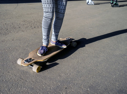  Young girl riding on a longboard in city