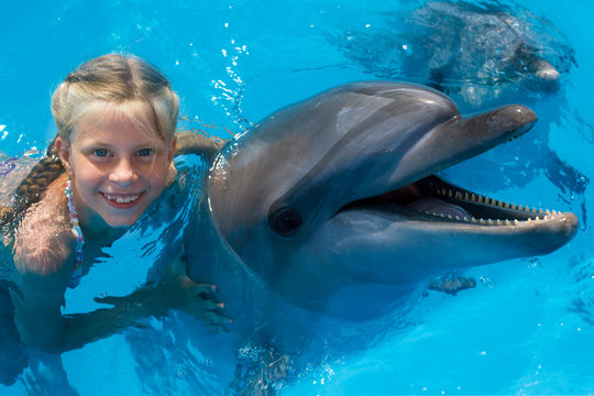Happy child and dolphins in blue water. Dolphin Assisted Therapy