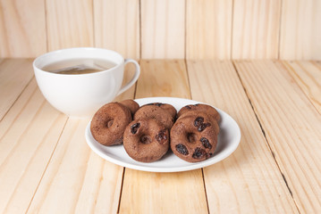 Chocolate donut in white plate with hot tea