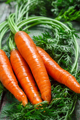 A bunch of young organic carrots with leaves on a wooden table. Vegetables from the garden
