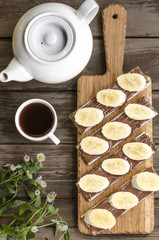 Breakfast crackers with chocolate paste and bananas, coffee and fruit   