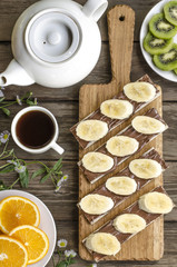 Breakfast crackers with chocolate paste and bananas, coffee and fruit   