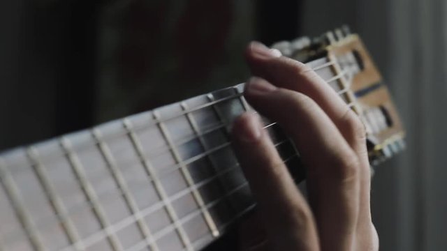 The man plays on a classical acoustic guitar neck shot