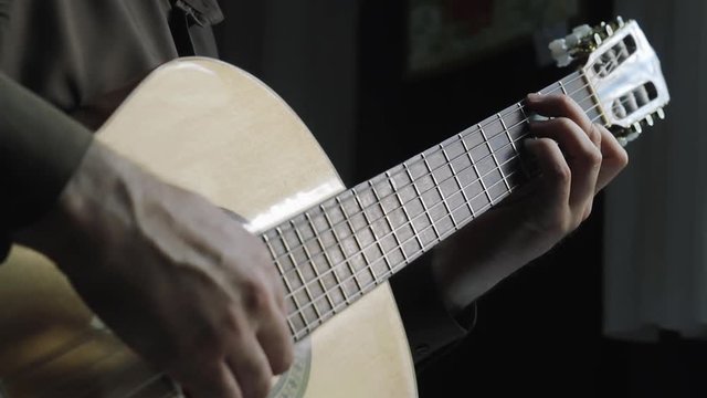 The man plays on a classical acoustic guitar