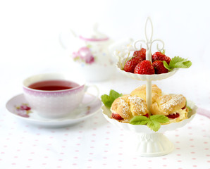Cream puff cakes or profiterole filled with whipped cream served with strawberries in plateau