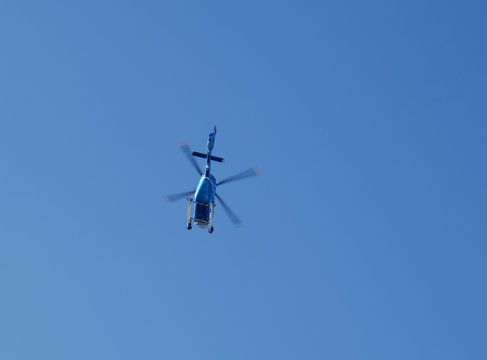The helicopter flying in the blue sky photographed from below.