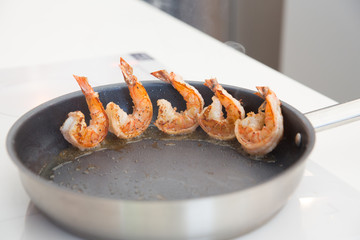 Королевские креветки обжариваются в масле на сковороде