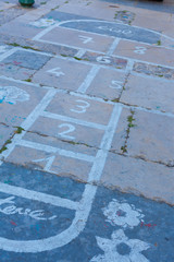 Hopscotch on an asphalt floor with chalk drawings of numbers and