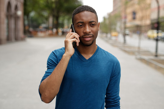 Young Black Man In City Walking Talking On Cell Phone