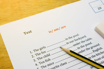 english test on brown wooden desk with gradient light