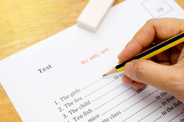 hand holding pencil over english test with gradient light