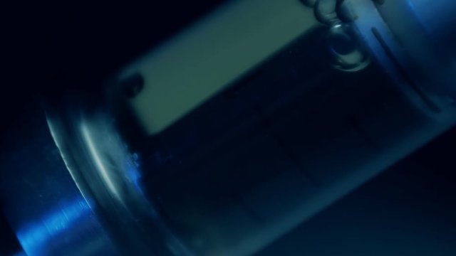 Glass syringe with the drug heroin on black background. Macro