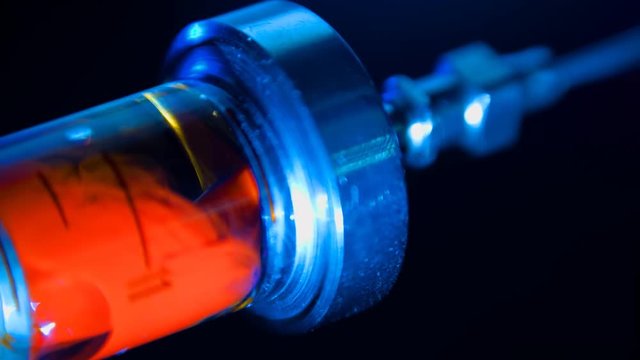 Glass syringe with the drug heroin with blood and air booble on black background