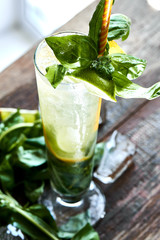 Alcoholic cocktail Mojito consists of rum, mate, Basil and Limoncello in a glass on a wooden table