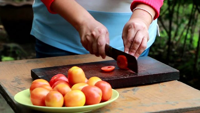 urban chef cutting up a tomato with a knife