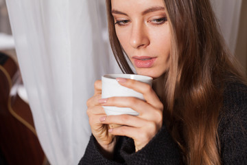 Woman near window drinking coffee