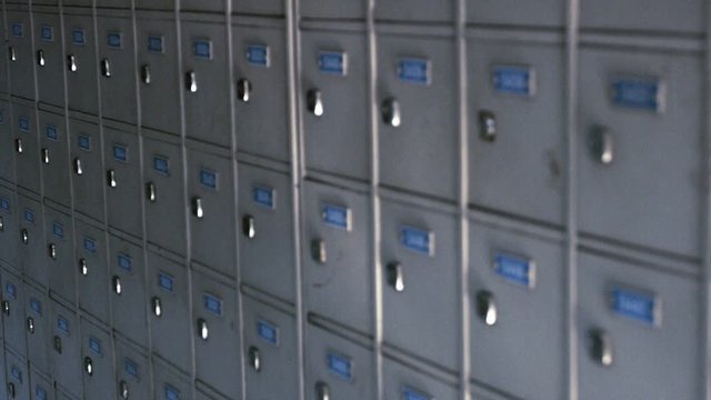 Video 1920x1080 - Continuous, row upon row of identical, gray painted post office boxes with neatly printed numbers and shiny locks.