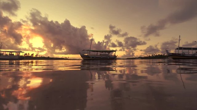 Sunset scene featuring boats docked in tranquil waters on the coast of a remote island in Nordeste Bahia, Brazil