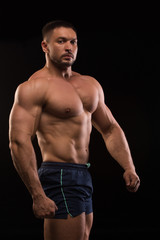 Fototapeta premium handsome muscular bodybuilder posing on a black background