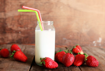 wooden table with strawberries and milk in a glass