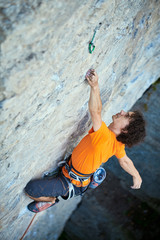 male rock climber. rock climber climbs on a rocky wall. a man hanging by one hand and resting. focus on the hand