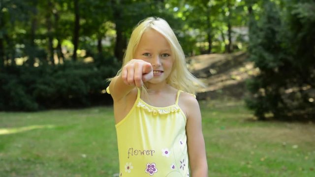 little young happy girl stands in the park and shows on you with finger - nod - agree - close by