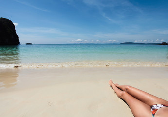 Fototapeta na wymiar Legs of young woman on the beach
