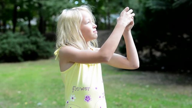 little smiling girl takes photos of nature - she looking around herself and looks for the new shoots