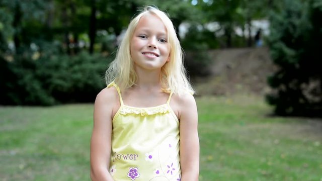 little cute smiling girl nods her head - agree - she stands in the park