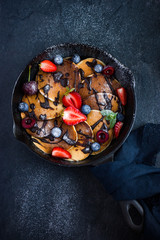 pancakes with fresh berries and chocolate sauce on pan, black ba