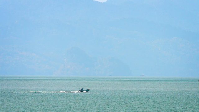 Video 1920x1080 - Small motorboat with a single crew, cruising at full throttle towards the crumbling seacliffs of an exotic, tropical island.
