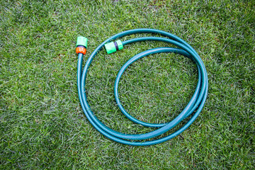Reel of hose pipe and spraying head on grass. Flat lay.