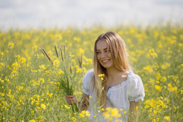 girl with a wreath of colorful flowers on her head, in a flowering yellow field