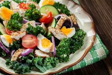Fresh salad with chicken, tomatoes, eggs and lettuce on plate