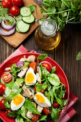 Fresh salad with chicken, tomatoes, eggs and arugula on plate