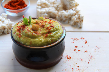 Avocado hummus served with hot chili pepper  and  rice toasts on wooded background