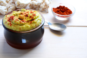 Avocado hummus served with hot chili pepper  and  rice toasts on wooded background