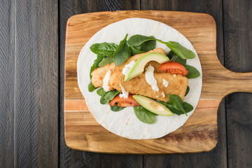 Crumbed fish fillet burrito with avocado and tomato