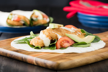 Crumbed fish fillet burrito with avocado and tomato