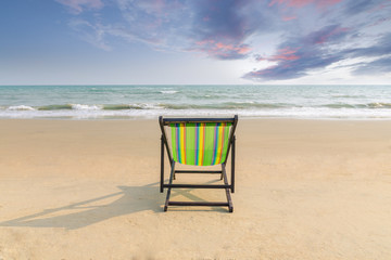 Beach chair on the white sand beach with sunset twilight sky and copy space. Summer background. Summer landscape concept. Romantic time in summer beach. Summer banner for label text or advertisement.