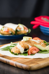 Crumbed fish fillet burrito with avocado and tomato