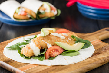 Crumbed fish fillet burrito with avocado and tomato