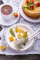 Homemade breakfast. Fresh cheesecake with berries ripe northern rare cloudberries on a wooden background  vintage handmade embroidered tablecloth. Served  white ceramic dishes