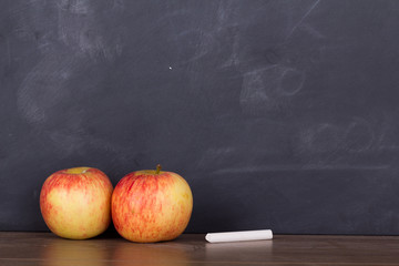 Apple on a wooden surface against a blackboard