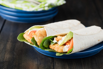 Crumbed fish fillet burrito with avocado and tomato