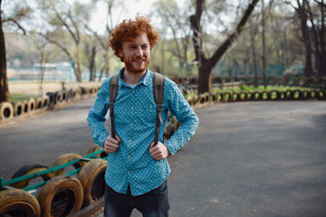 Outdoor lifestyle portrait of handsome ginger guy with backpack